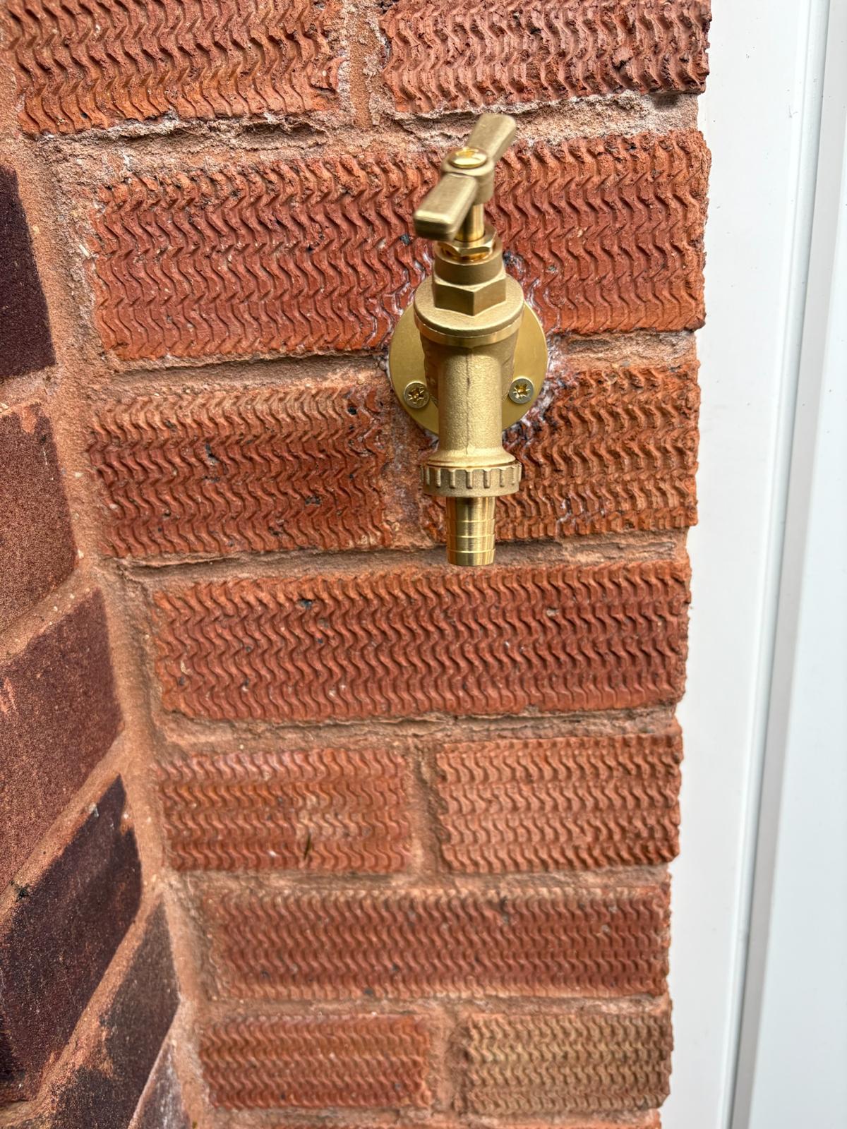 Brass outdoor tap fitted to brick wall