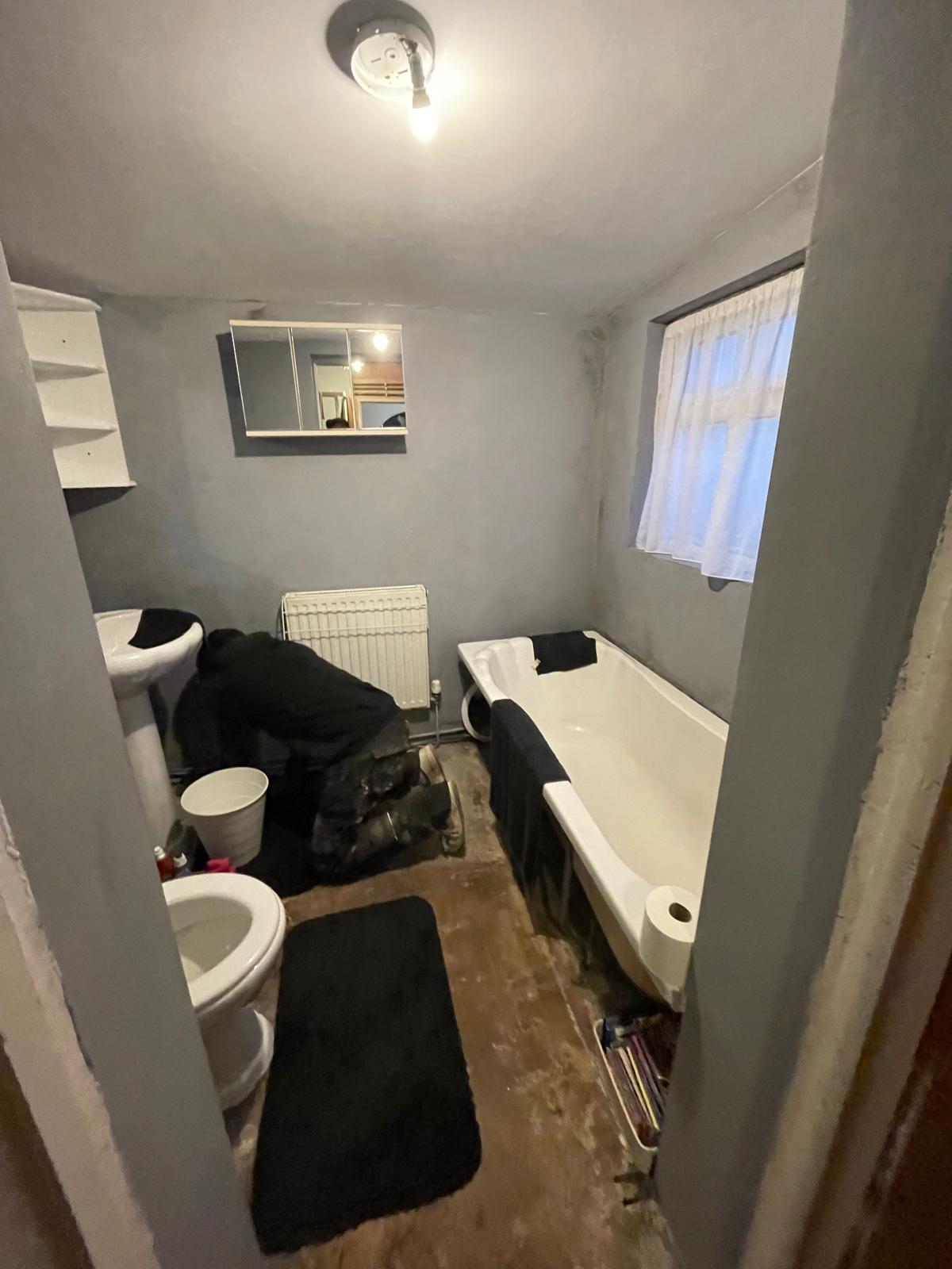 Bathroom before renovation - dated fixtures and worn flooring